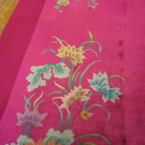 Magenta rug with yellow, blue, and green floral motifs borders a light plank wood floor.