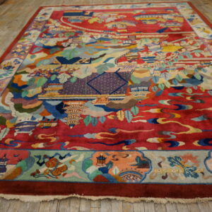 High-pile crimson rug displaying a multicolored, detailed landscape and architectural scene on a hardwood floor.