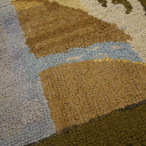 High-texture rug detail showing irregular loops in tan, light blue, olive, and gray areas.