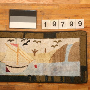 Hooked rug with a beige, blue, and green sailboat scene border sits on natural hardwood planks.