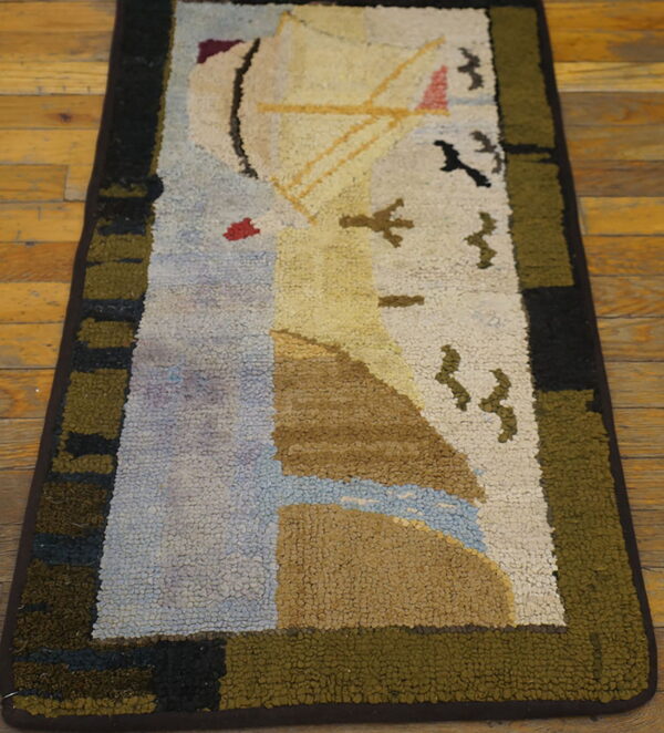 Chunky hooked rug depicting a sailboat and birds, framed by olive and black stripes, on wood planks.
