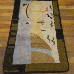 A colorful loop pile area rug with an abstract sailboat design rests on distressed hardwood flooring.