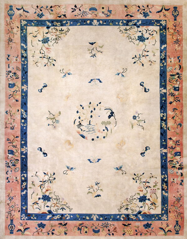Low-pile rug with a cream field, pink and blue borders, and scattered stylized floral designs.