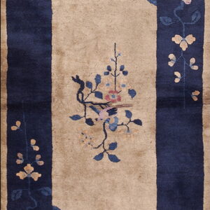 Long beige runner rug with a wide navy blue border and stylized floral motifs in pink and coral.