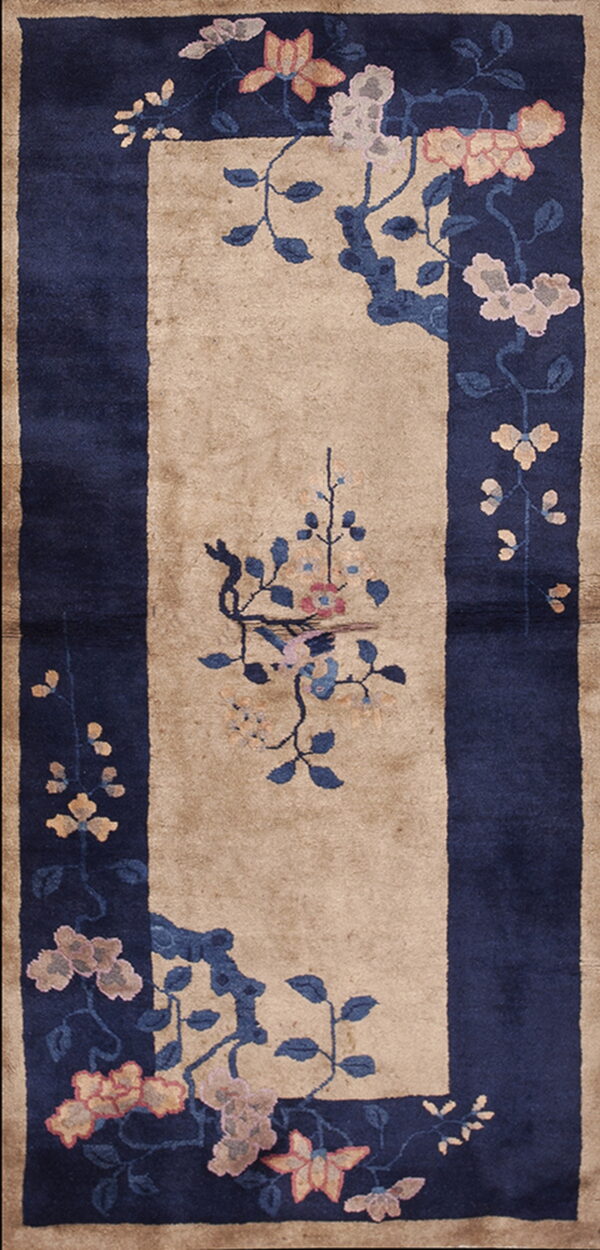 Long beige runner rug with a wide navy blue border and stylized floral motifs in pink and coral.