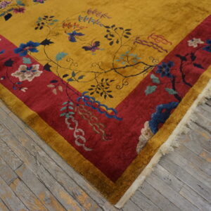 Plush yellow rug with a crimson border and intricate floral vine patterns rests on weathered gray wood flooring.