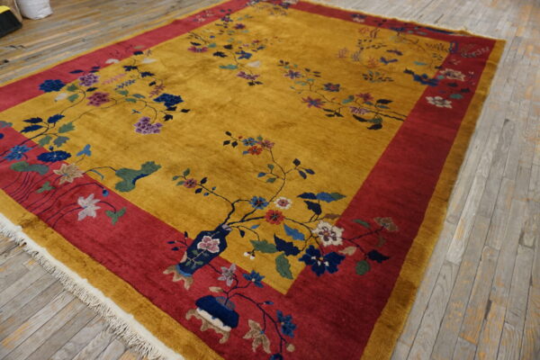 Golden yellow high-pile rug with sprawling blue and purple floral vines and a wide red border on wood flooring.
