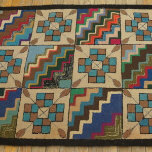 Textured rug with a multicolored zigzag and checkerboard block pattern lying on light wood flooring.