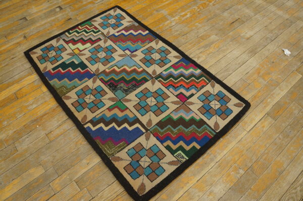 A colorful geometric rug with checkered diamonds and zigzag stripes rests on worn, light wood planks.