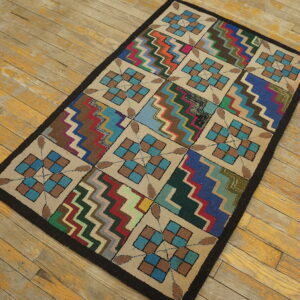 Multicolor hooked area rug with block geometric and chevron patterns displayed on distressed wooden flooring.