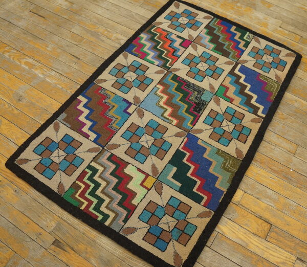 Multicolor hooked area rug with block geometric and chevron patterns displayed on distressed wooden flooring.