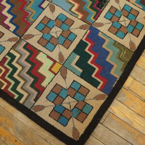 Multi-colored, textured rug with geometric squares and zigzags lies diagonally on yellowed hardwood planks.