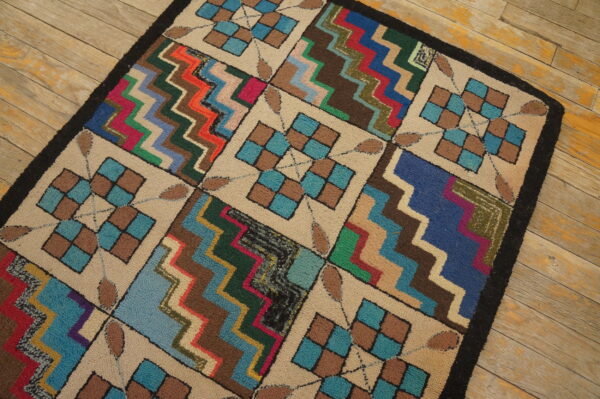 Multi-colored textured rug featuring checkerboard and zigzag blocks rests on rustic wooden planks.