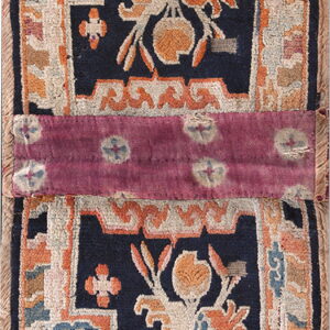 Stylized navy and rust rug with floral patterns, vertically split by a magenta dyed fabric band.