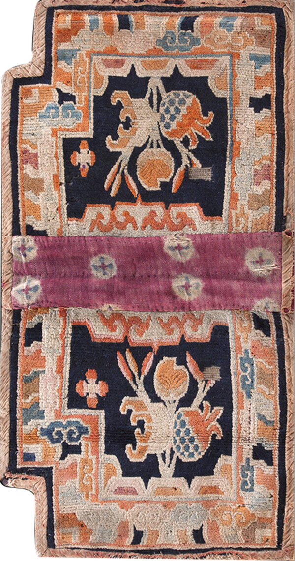 Stylized navy and rust rug with floral patterns, vertically split by a magenta dyed fabric band.