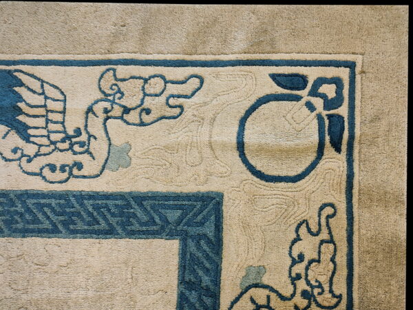 Beige rug detail with teal blue borders, stylized bird, cloud, and geometric corner patterns.