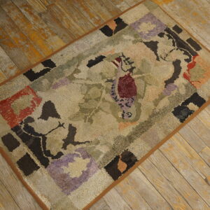 A textured rug with an abstract floral pattern in beige, green, burgundy, and purple sits on weathered wooden planks.