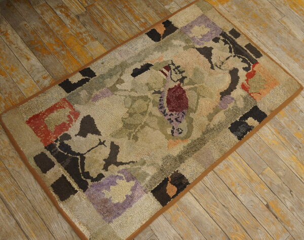 A textured rug with an abstract floral pattern in beige, green, burgundy, and purple sits on weathered wooden planks.