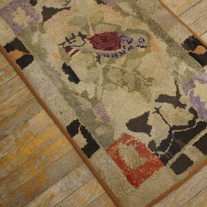 Muted beige textured rug with abstract burgundy, purple, and black shapes rests on distressed wood flooring.