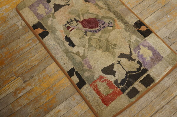 Muted beige textured rug with abstract burgundy, purple, and black shapes rests on distressed wood flooring.