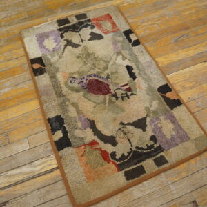 A looped rug featuring beige, purple, red, and black abstract designs rests on rustic wooden planks.