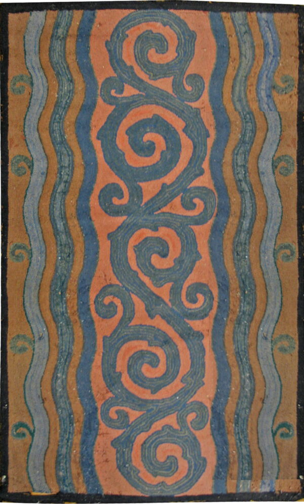 Rug displays large blue serpentine scrolls on a coral field, flanked by vertical wavy blue and tan stripes.