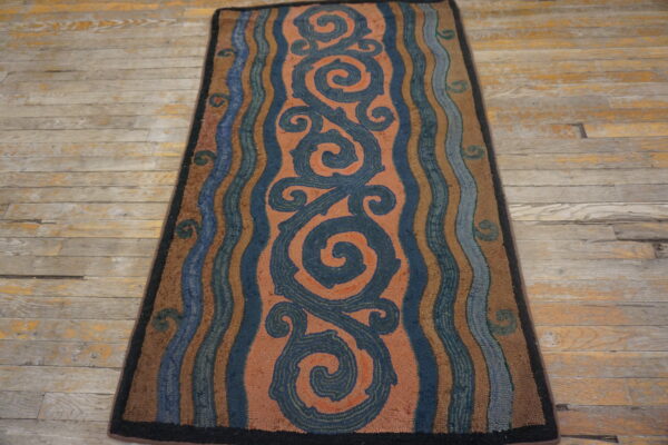 Textured runner rug with large navy scrolls on a salmon field and wavy borders on distressed wood planks.