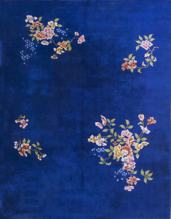 A deep blue rug with a plush texture displays scattered clusters of multicolored floral motifs.