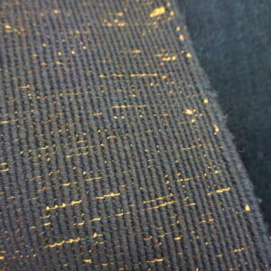 Close-up of a dark blue ribbed rug with tan speckles resting on a light wooden surface.