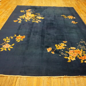 Large deep blue rug with scattered peach, yellow, and cream floral patterns on wooden floorboards.
