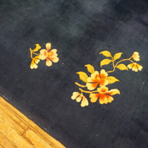 Dark blue rug with gold and orange floral patterns sits on light wooden floorboards.