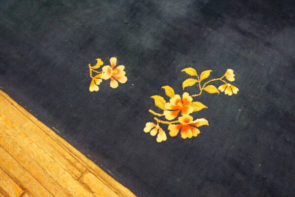 Dark blue rug with gold and orange floral patterns sits on light wooden floorboards.