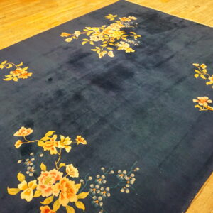 Deep blue high-pile rug featuring large scattered yellow and peach florals rests on golden hardwood flooring.