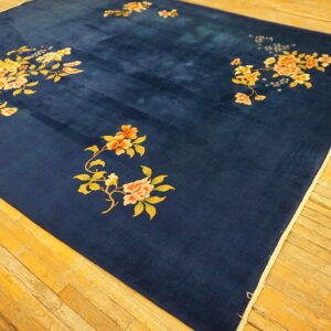 Velvety indigo rug featuring scattered peach and yellow blossoms rests on a distressed wood floor.