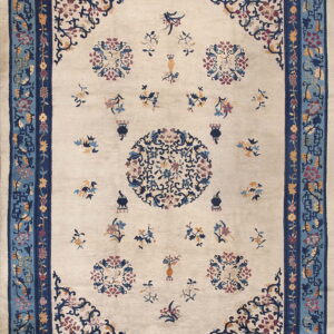 Light beige rug with scattered multicolored floral motifs and intricate multi-toned blue borders.
