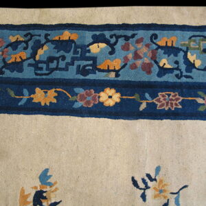 A cream field is bordered by bands of dark blue and patterned teal featuring gold and maroon floral motifs.