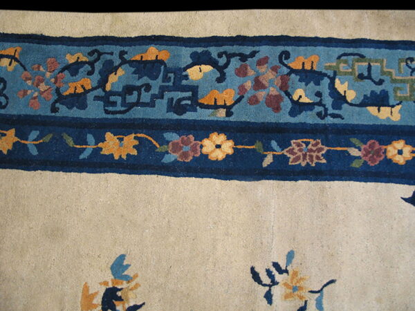 A cream field is bordered by bands of dark blue and patterned teal featuring gold and maroon floral motifs.