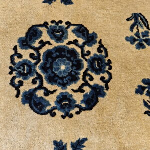 Detail of a medium-pile beige rug with a deep blue traditional floral medallion and floral motifs.