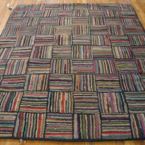 Multicolored striped high-pile rug laid in a repeating rectangular block pattern on a wooden floor.