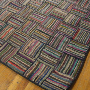 Multicolored braided rug featuring a basketweave pattern of textured strips on a wood floor.