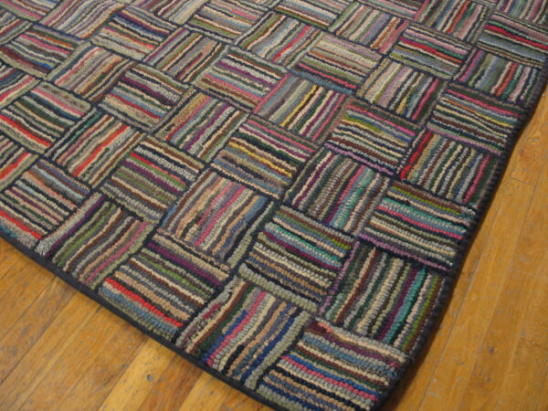 Multicolored braided rug featuring a basketweave pattern of textured strips on a wood floor.