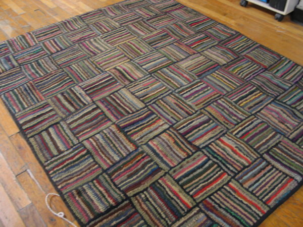 Highly textured, multicolored rug with a geometric striped block design on wood planks.