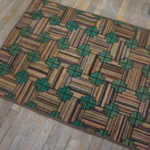 Multicolored striped rug featuring teal geometric patterns rests on distressed gray wood flooring.