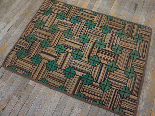 Multicolored striped rug featuring teal geometric patterns rests on distressed gray wood flooring.