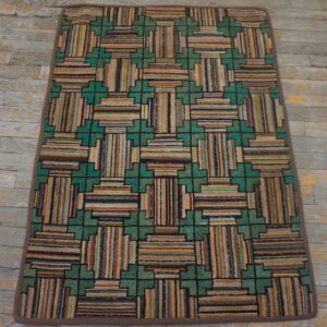 Multicolor striped low-pile rug with a teal green geometric framework on distressed gray hardwood floors.