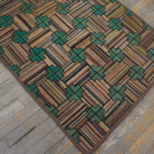 A textured rug with multicolored striped blocks and teal geometric shapes rests on distressed wood flooring.