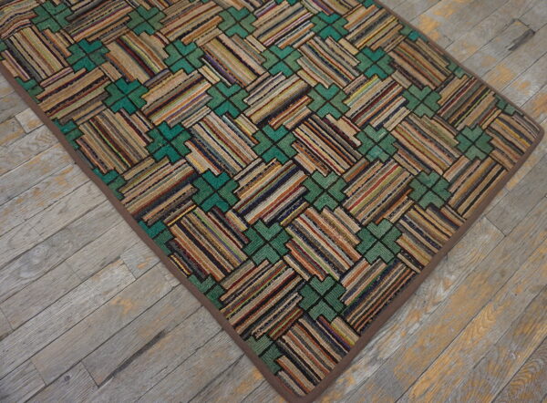A textured rug with multicolored striped blocks and teal geometric shapes rests on distressed wood flooring.