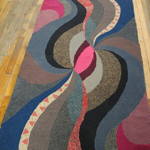 Abstract runner rug with swirling bands of pink, blue, gray, and brown colors on light plank flooring.