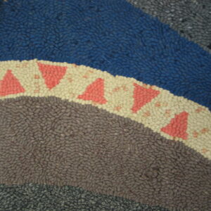 Looped rug texture featuring concentric bands of blue, brown, and cream with coral triangles.