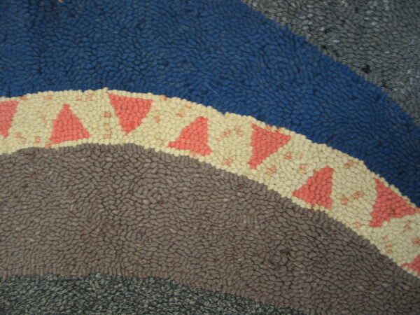 Looped rug texture featuring concentric bands of blue, brown, and cream with coral triangles.